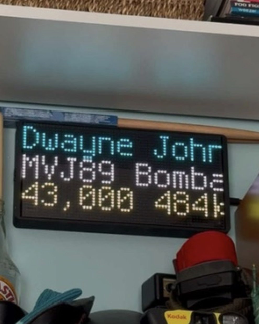 NearestPlane display on a bookshelf, naming a private jet passing overhead at 43,000 feet